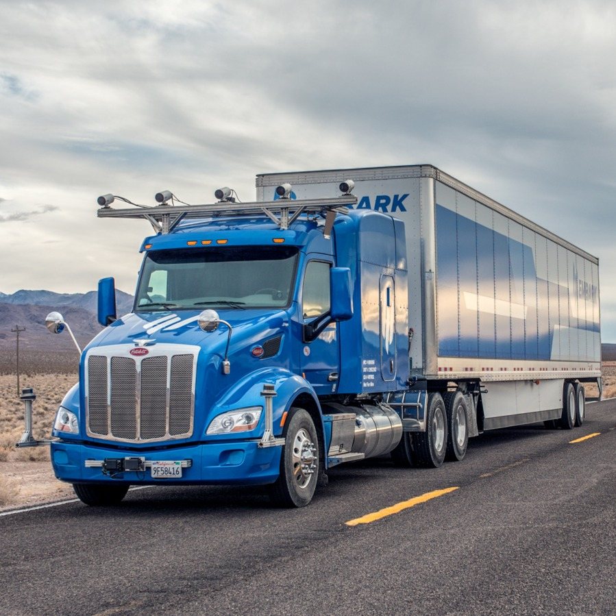 Embark's blue Peterbilt with a trailer on a desert highway in Nevada, with a camera rack across the cab roof and sensor mounts at the front corners and on the bumper