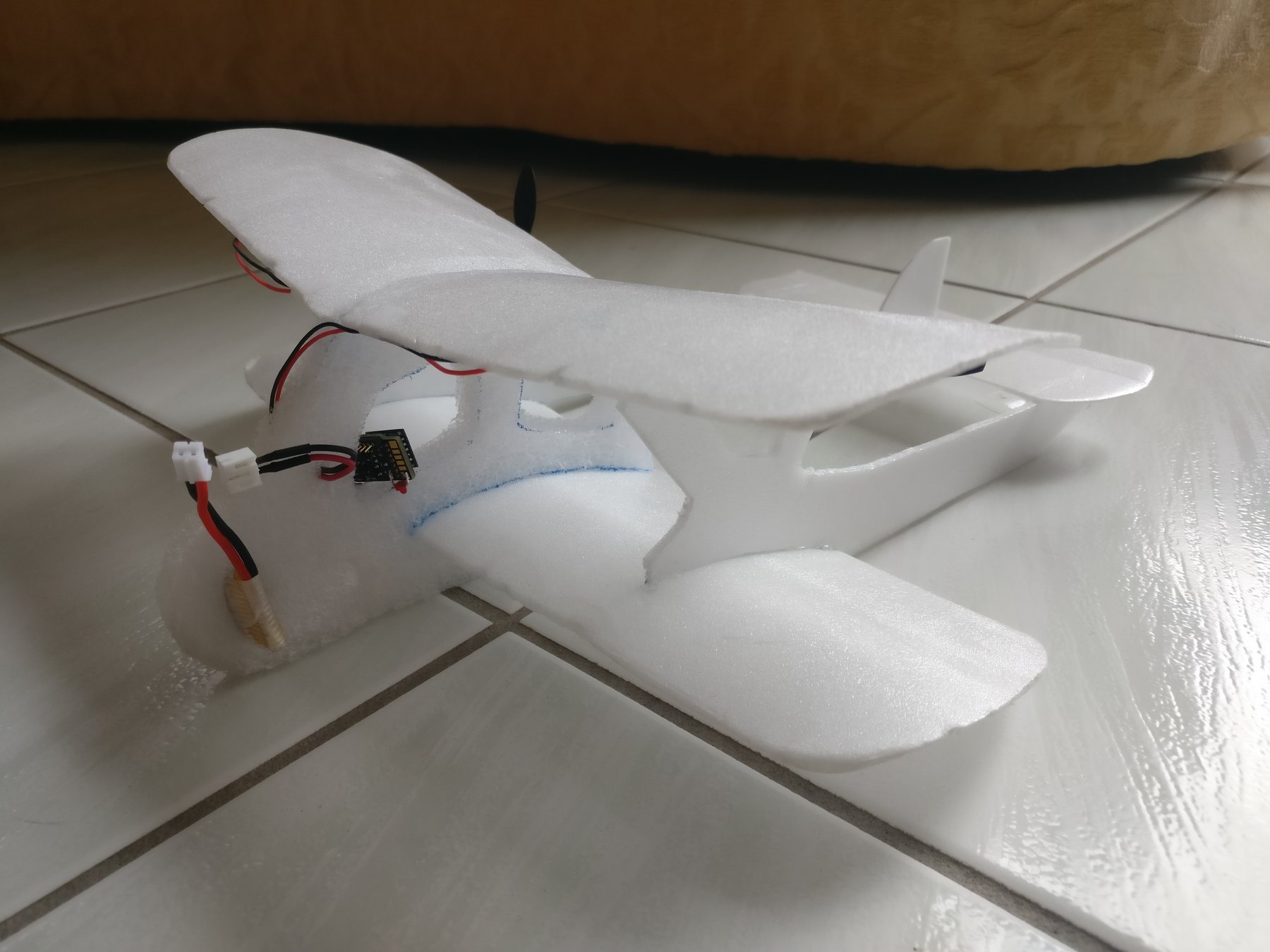 The 20 g two-motor indoor foam RC plane, with the controller board and its red LED mounted on the fuselage