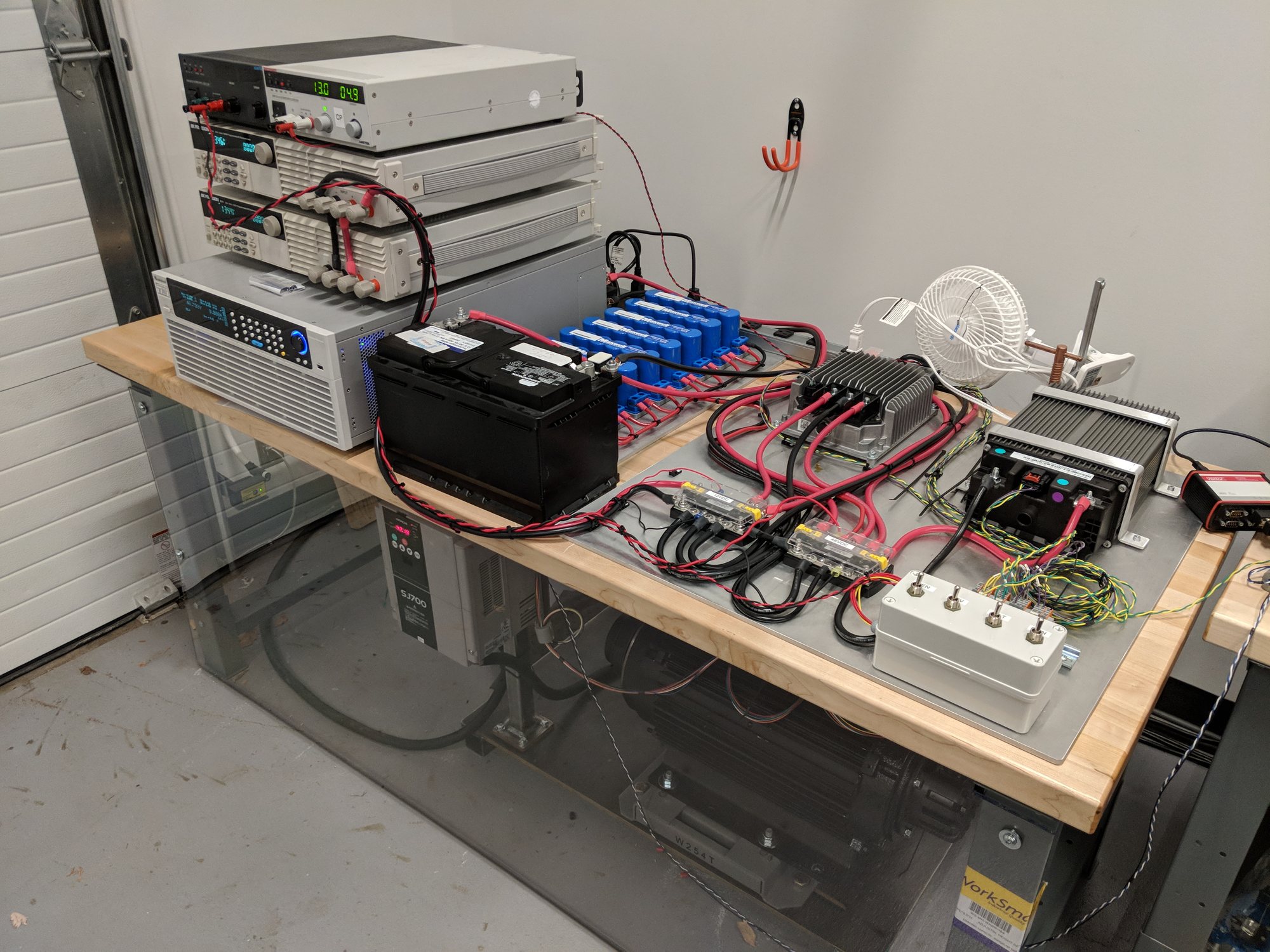 Bench test rig for the fault-tolerant power system: 12 V battery, capacitor bank, 12-to-48 V converter, 48 V battery and lab supplies, with a motor load under the desk